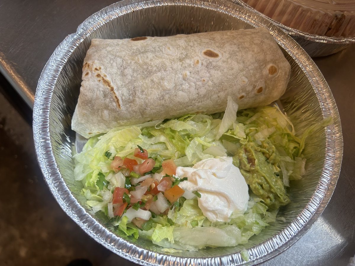 A burrito with a small salad and sour cream